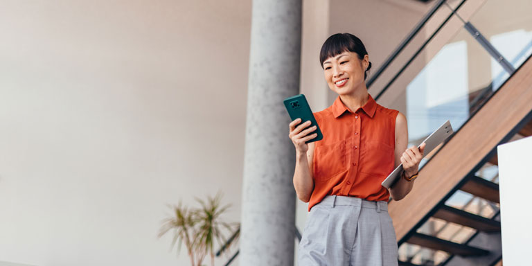 Office woman in orange shirt looking at mobile phone